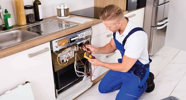 Technician checking a dishwasher electrical system with a multimeter