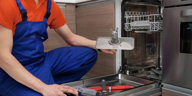 Technician removing and inspecting a dishwasher filter during maintenance