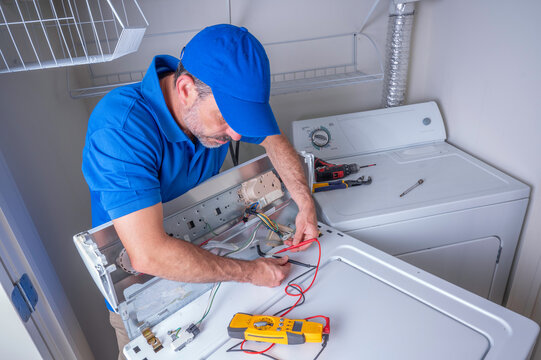 Technician testing wiring on a laundry appliance with a digital multimeter