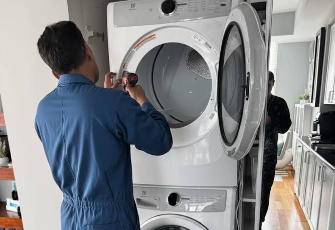 Technician servicing the open door and drum of a stacked dryer